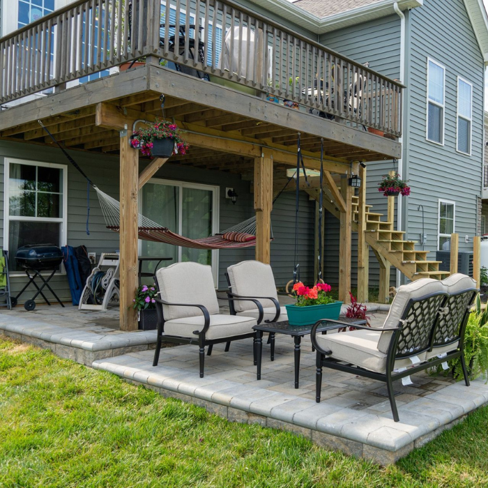 Deck Post Replacement walk out patio under a deck with seating, a hammock and landscaping