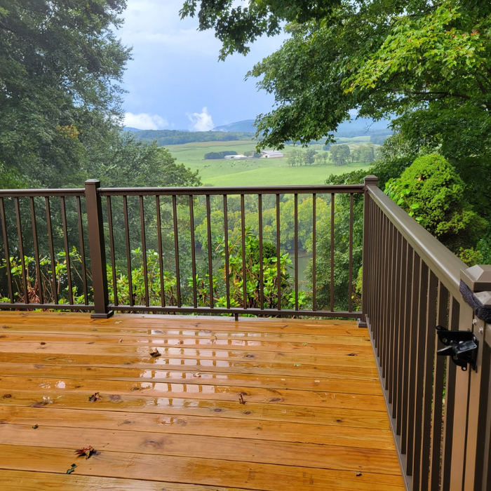 Decks wet wooden deck with railings and rolling green hills in the distance