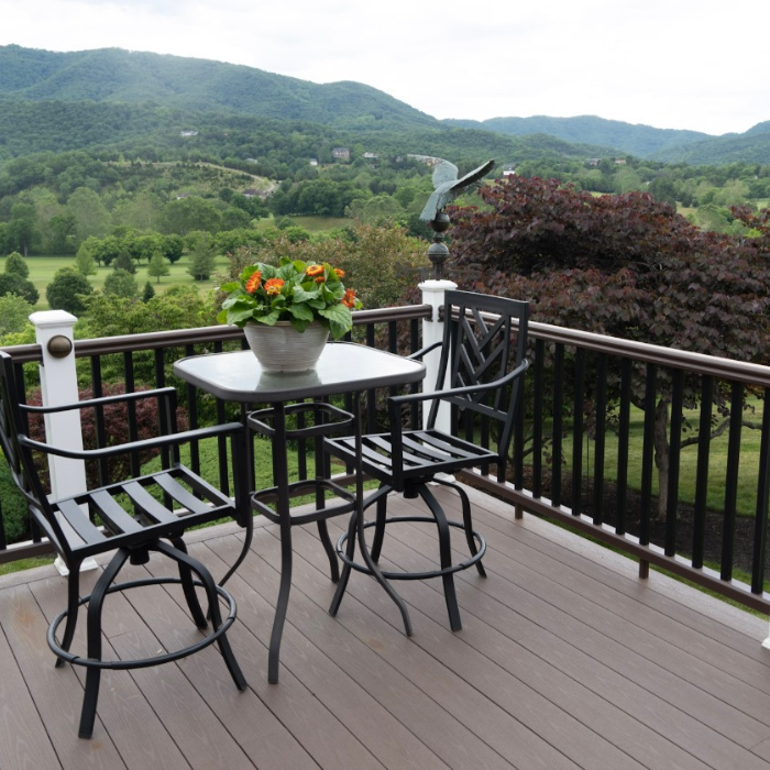Railings deck with table and chairs and a railing high up with mountains in the distance