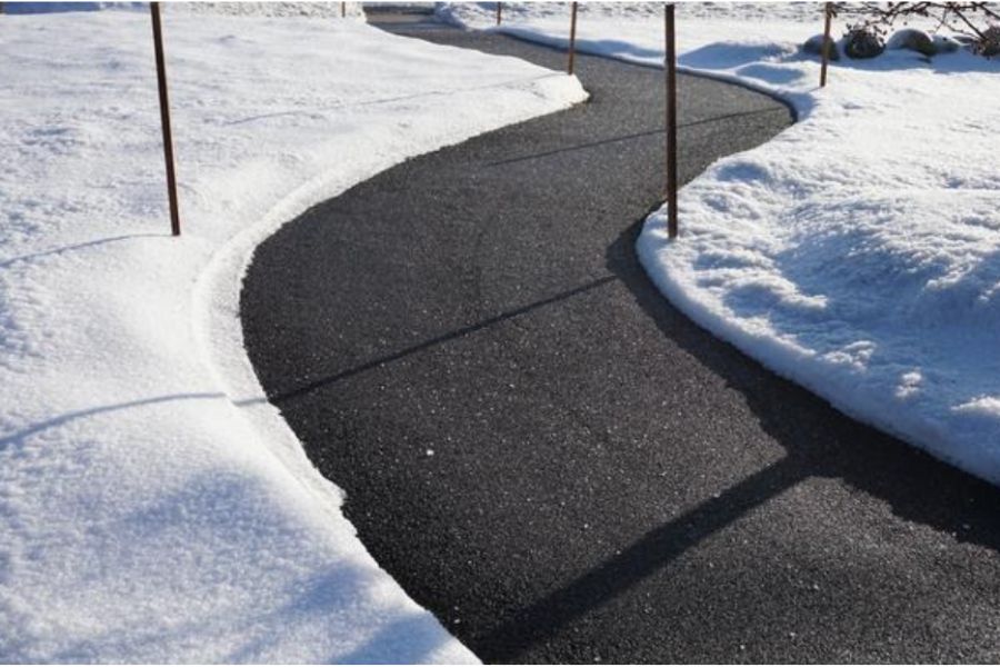 Clean, curved asphalt pathway cleared of snow, surrounded by snowbanks on both sides, showcasing effective winter snow removal.