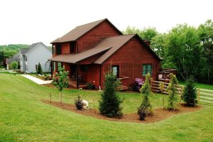 Cabin with green grass yard and plant with mulch.